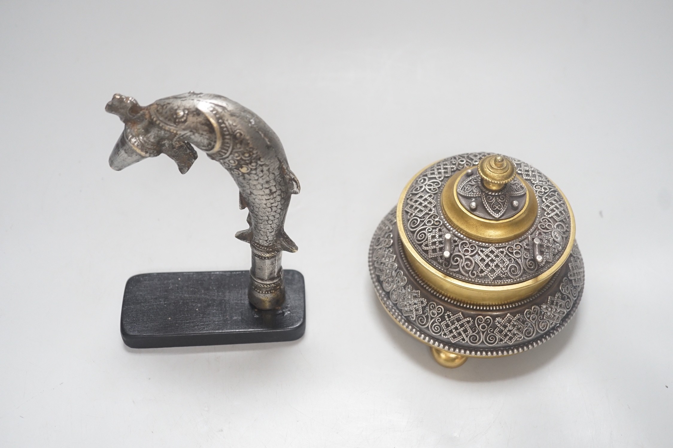 A Continental silvered and gilt metal inkwell, c.1900, and an Indo-Persian silvered bronze ‘fish’ tap or cane handle on stand, 16cm